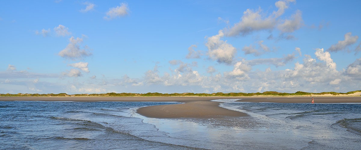 Priel und Sandbank im Watt unter Sommerwolken