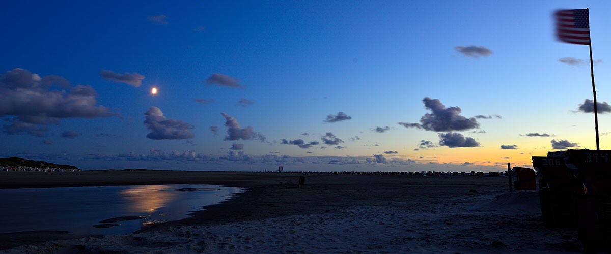 Strand in der Dämmerung, am Himmel steht der Mond