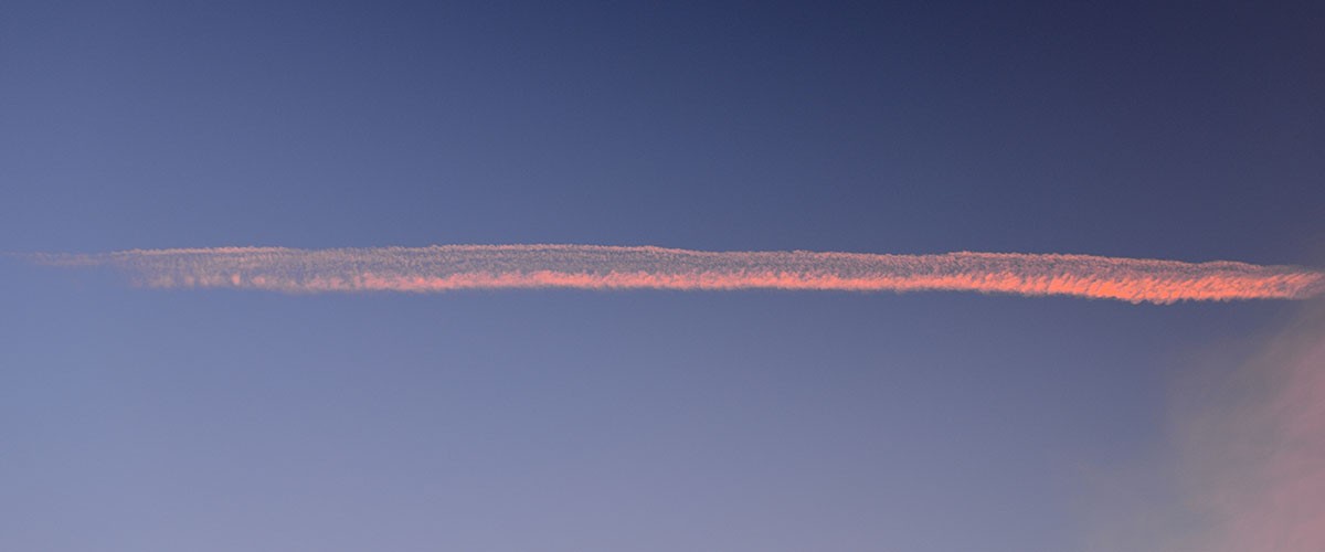 Schmales rosa Wolkenband über dem ruhigen Meer
